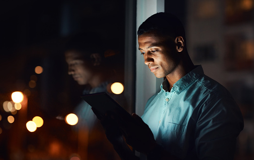 Shot of a handsome young businessman using a digital tablet while working late in his office