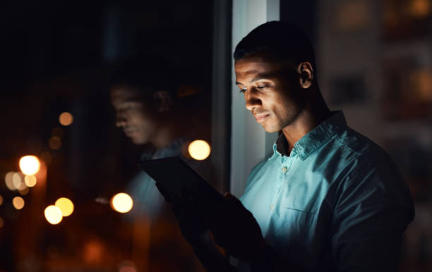 It's time you also get connected Shot of a handsome young businessman using a digital tablet while working late in his office working late stock pictures, royalty-free photos & images
