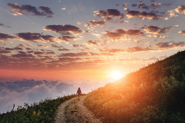 mujer en el sendero admirando la puesta de sol con nubes y niebla. - mountain footpath hiking backpacker fotografías e imágenes de stock