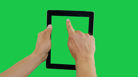 Pointing Finger Clicking Top Center On Device Screen with Green Background. Digital Tablet Green Screen. Use in any project that depicts finger, gesture, touchscreen and the like.