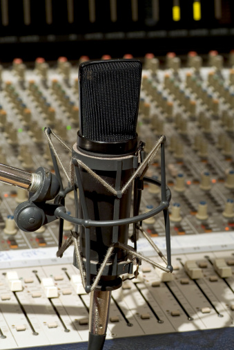 Tight close up of microphone over a studio control board.