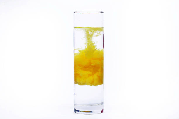 istock Yellow paint falls in a glass with water 1158602393