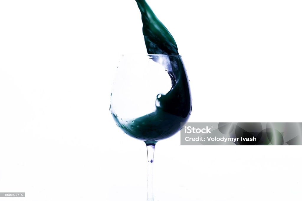 Green and violet water splashes in a wineglass Advertisement Stock Photo