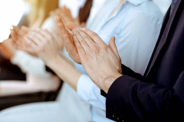Business people clapping and applause at meeting or conference, close-up of hands. Group of unknown businessmen and women in modern white office. Success teamwork or corporate coaching concept. gente de negocios aplaudiendo y aplaudiendo en la reunión o conferencia, primer plano de las manos. grupo de hombres de negocios y mujeres desconocidos en la oficina blanca moderna. trabajo en equipo de éxito o concepto de coaching corporativo.