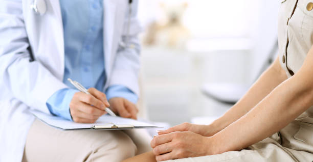 istock Doctor and patient talking. Physician at work in hospital while writing up medication history records form on clipboard near sitting woman. Healthcare and medicine concepts. 1158602843