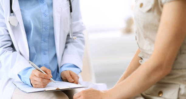 istock Doctor and patient talking. Physician at work in hospital while writing up medication history records form on clipboard near sitting woman. Healthcare and medicine concepts. 1158602852