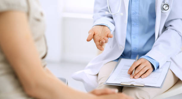 istock Doctor and patient talking. Physician at work in hospital while writing up medication history records form on clipboard near sitting woman. Healthcare and medicine concepts. 1158602859