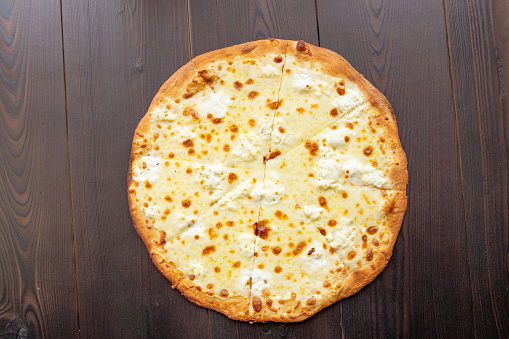 Homemade simple pizza with cheese on wooden background