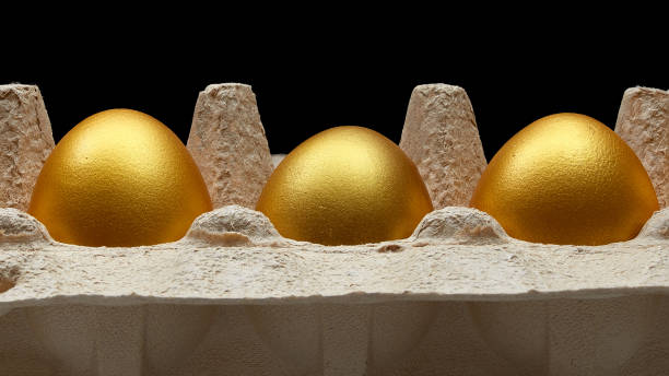 istock Gold eggs in a carton on black background 1158604598