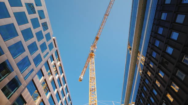 A large tower crane in the downtown of the modern city. Glass office buildings around. Low angle wide shot stock photo