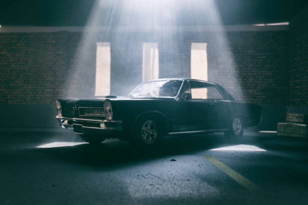 Model Pontiac GTO In Atmospheric Garage Beaconsfield, UK - June 26, 2019: A scale model of a Pontiac GTO in an old garage setting. The model car is sitting in an atmospherically-lit industrial garage environment. The garage environment/model is made out of fibre-board, and was photographed in my studio in Beaconsfield. There is no one in the photograph. diorama photos stock pictures, royalty-free photos & images