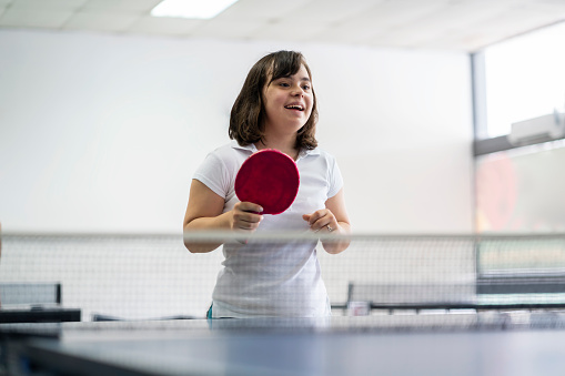 Teen girl with down syndrome playing table tennis