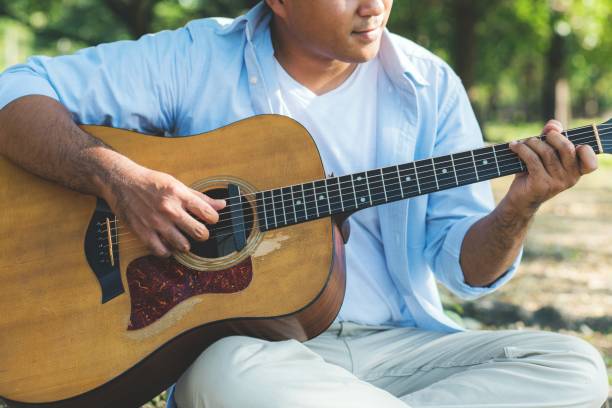 istock Young asian man playing guitar in park 1158614054