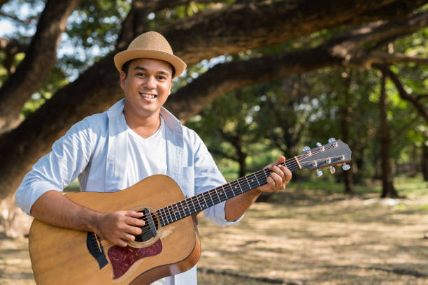 istock Young asian man playing guitar in park 1158614056