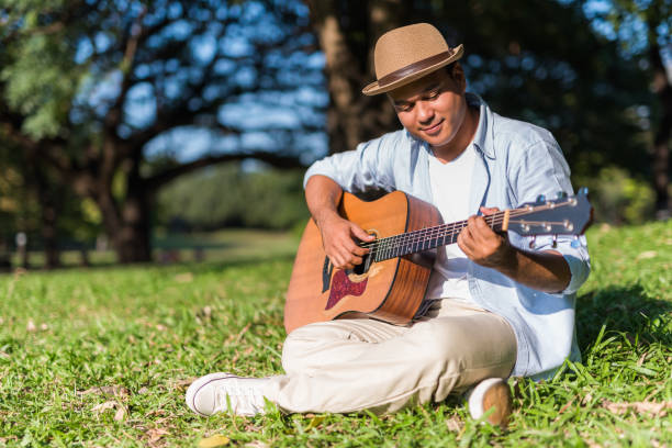 istock Young asian man playing guitar in park 1158614060