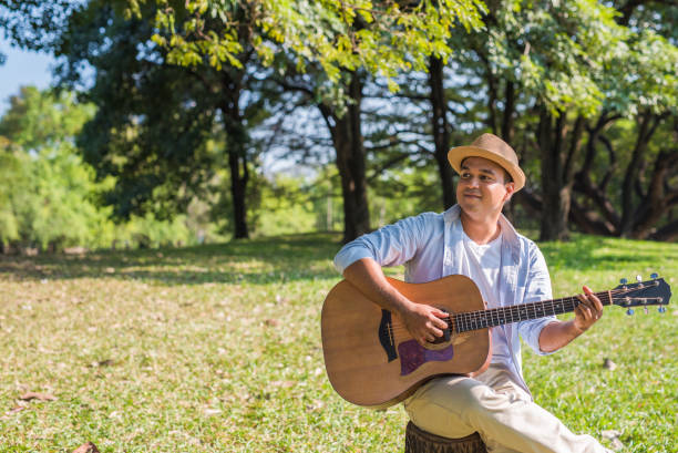 istock Young asian man playing guitar in park 1158614265