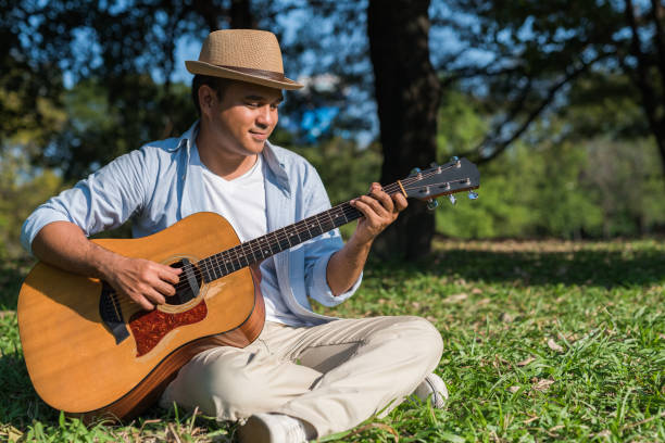 istock Young asian man playing guitar in park 1158614963