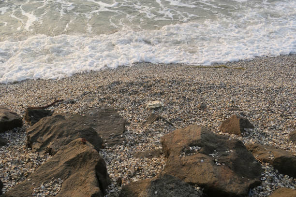 large beach pebbles in waves during sunset as background