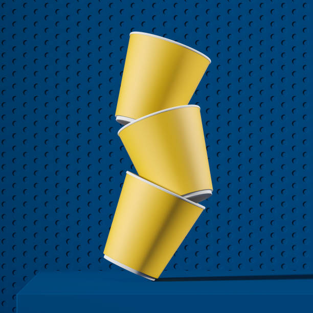 pila di tazze di carta gialla che cadono sul tavolo blu - disposable cup cup stack blue foto e immagini stock
