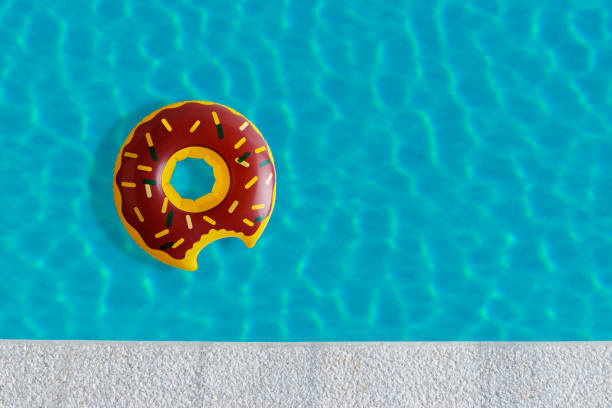 istock Inflatable donut pool toy in swimming pool with sun reflection. Minimal summer concept. 1158619531