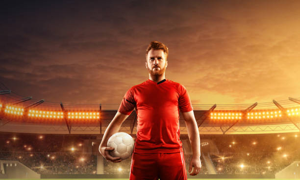 istock Soccer player with a ball on a floodlit stadium. 1158619681