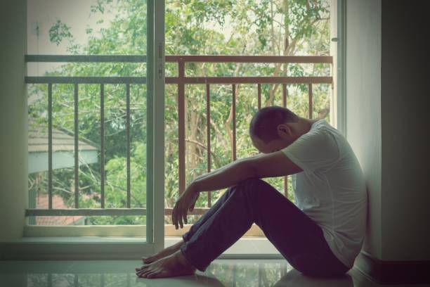 istock depressed man sitting in dark room 1158619742
