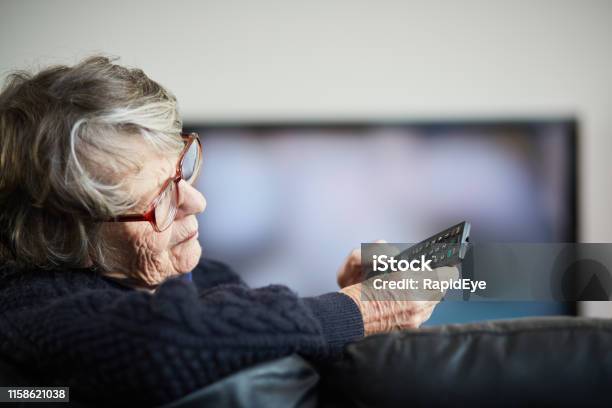 Senior Woman Irritated By Her Tv Remote Control Stock Photo - Download Image Now - Watching TV, 70-79 Years, Senior Adult