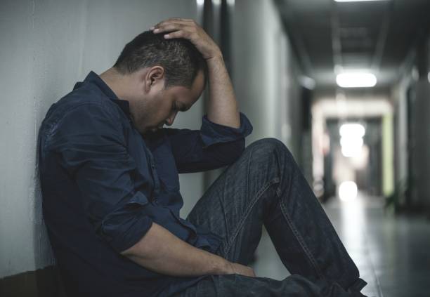 istock depressed man sitting in dark room 1158621926