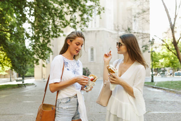 two female tourists eating souvlaki in athens - opa! souvlaki of greece imagens e fotografias de stock