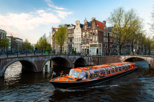 амстердам канал круизное судно с нидерландами традиционный дом в амстердаме, нидерланды. - amsterdam canal netherlands dutch culture стоковые фото и изображения