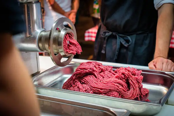 People watching beef being minced by a meat chopper machine