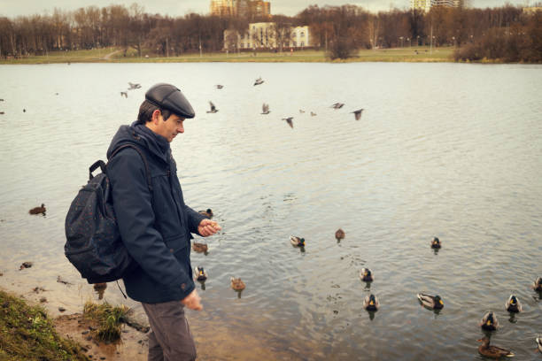 Handsome dark-haired middle-aged man in jacket, cap and backpack