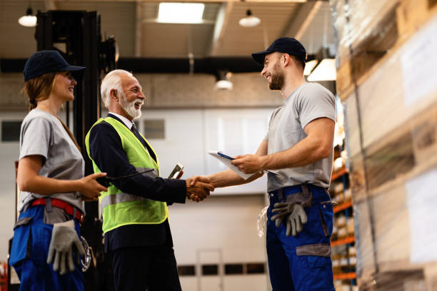 ниже вид счастливого старшего бизнесмена рукопожатие со складом работника. - manual worker handshake industry warehouse стоковые фото и изображения