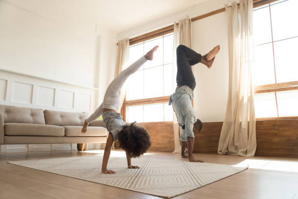 sporty active père et fille d'amérique d'afrique faisant le handstand - équilibre sur les mains photos et images de collection