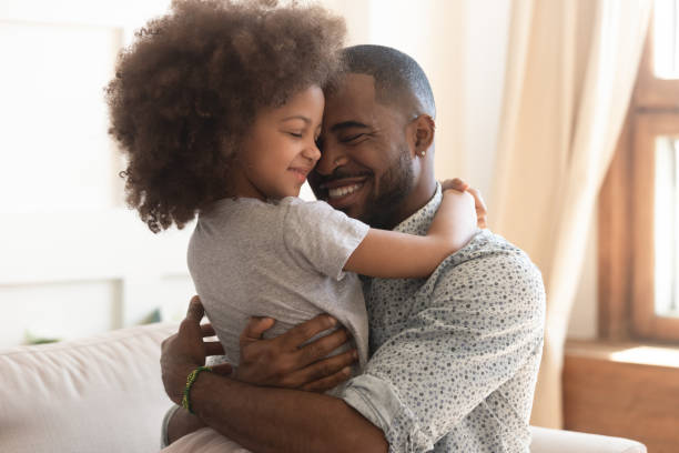 felice padre africano che tiene abbraccia la figlia carina bambino - gender bender foto e immagini stock