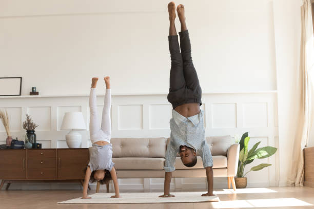 istock Active african kid girl copy father doing handstand at home 1158625005