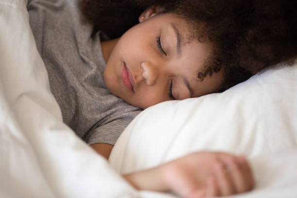 cute little african american kid girl sleeping alone in bed - sleeping child bedtime little girls imagens e fotografias de stock