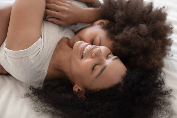 istock Affectionate african mom and child daughter embracing lying on bed 1158625029