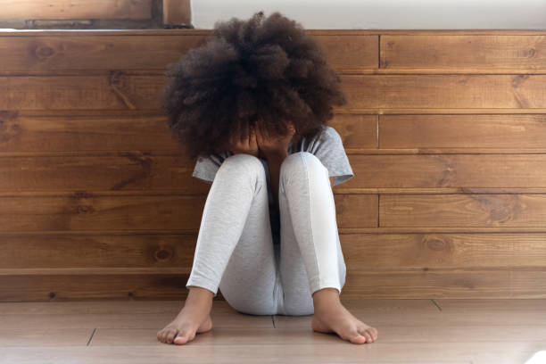 Sad stressed little african girl crying sit alone on floor Sad stressed little african american girl crying, upset lonely bullied child feels abandoned abused, preschool black orphan kid in tears sit alone on floor, children abuse, unhappy childhood concept punishment photos stock pictures, royalty-free photos & images