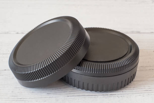 istock Camera lens caps and body covers on white painted wooden surface 1158628669