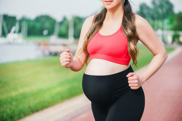 Happy pregnant woman jogging outside. stock photo