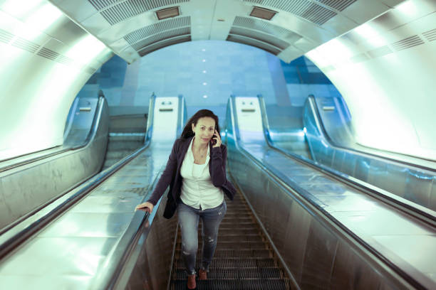 Mid adult casual businesswoman going up on an escalator. About 35 years old, Asian brunette.