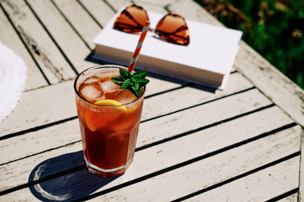 summer scene, iced tea with lemon and mint on a garden table in bright sunshine. - chá gelado imagens e fotografias de stock