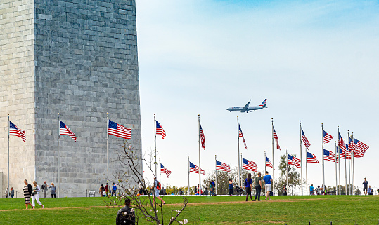 Washington D.C., USA, October 2016; people visiting the Washington Monument with a commercial airplane landing in the background