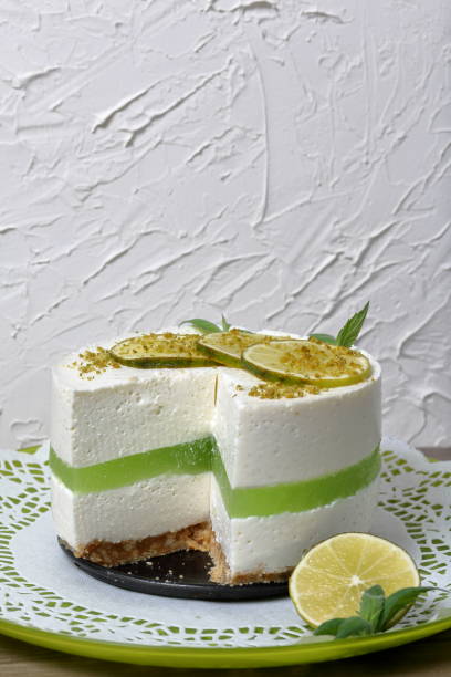 istock Lime cheesecake without baking. Lies on a plate. Decorated with lime slices. The piece is cut off. Against the background of white wall with decorative plaster. 1158635298