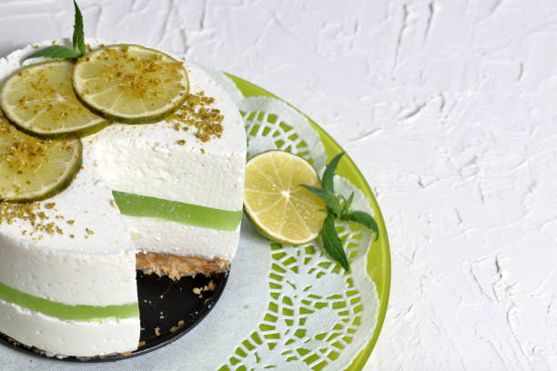 istock Lime cheesecake without baking. Lies on a plate. Decorated with lime slices. The piece is cut off. On the surface covered with decorative plaster white. 1158635314