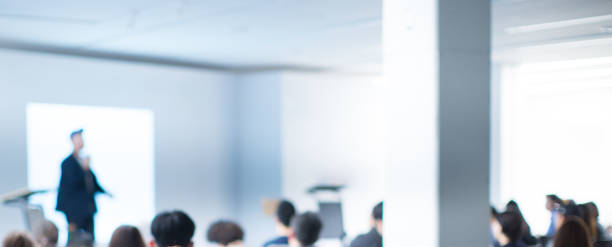 istock Speaker at Talk in Business Conference. Tech Executive Entrepreneur Speaker on Stage at Conference. Presenter Giving Business Presentation at Meeting. Corporate Exhibition for Investors Event. 1158635397
