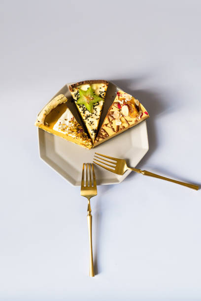 three pieces of a very sweet and delicious cake on a plate with a modern geometric design in gray. golden fork for eating. sugar addiction. - cheesecake syrup almond cream imagens e fotografias de stock