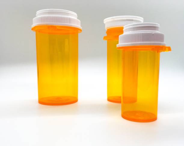 три пустые бутылки оранжевой таблетки на столе - medicine cabinet prescription pill bottle medicine стоковые фото и изображения