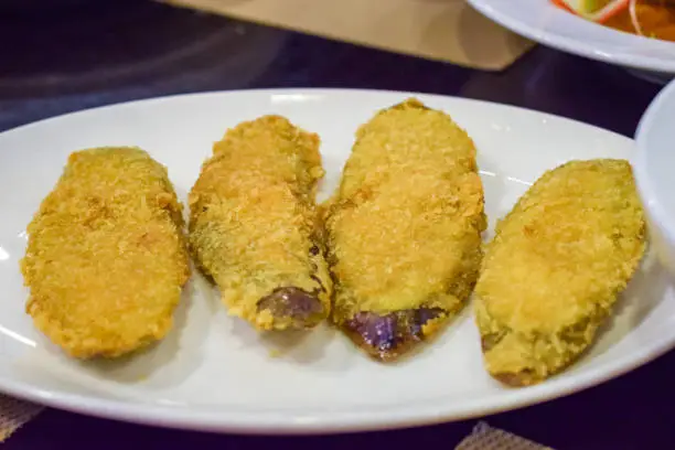 Tasty fried breaded eggplant on white plate in a restaurant